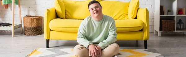 Happy teenager with down syndrome sitting on floor at home, banner — Stock Photo