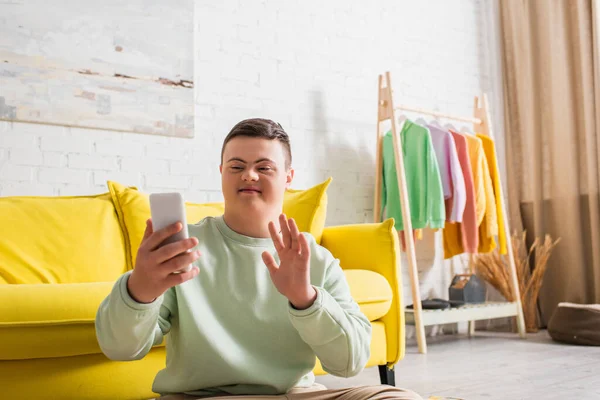 Boy with down syndrome having video call on smartphone at home — Stock Photo