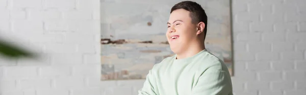 Adolescente feliz con síndrome de Down mirando hacia otro lado en casa, pancarta - foto de stock