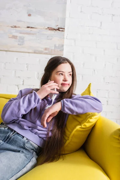 Teenagermädchen mit Down-Syndrom spricht zu Hause auf der Couch auf dem Smartphone — Stockfoto