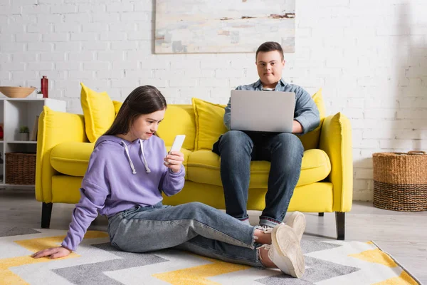Teen couple with down syndrome using devices at home — Stock Photo