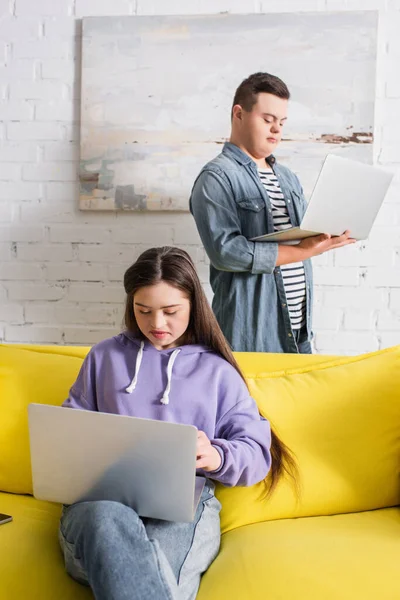 Teen girl with down syndrome using laptop near friend at home — Stock Photo