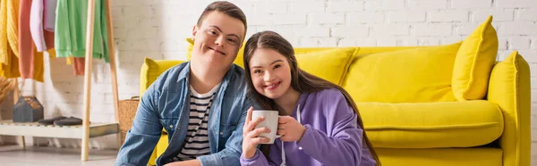 Sorrindo adolescente menina segurando copo e olhando para câmera perto namorado em casa, banner — Fotografia de Stock