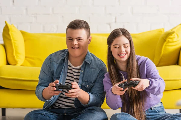 KYIV, UKRAINE - JANUARY 21, 2022: Positive teenagers with down syndrome playing video game at home — Stock Photo