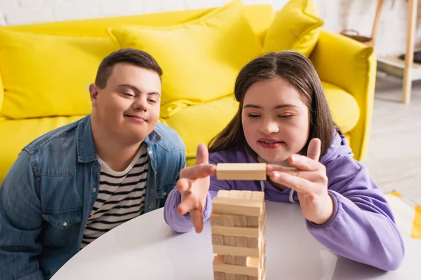 Adolescentes positivos com síndrome de down jogando blocos de madeira jogo em casa — Fotografia de Stock