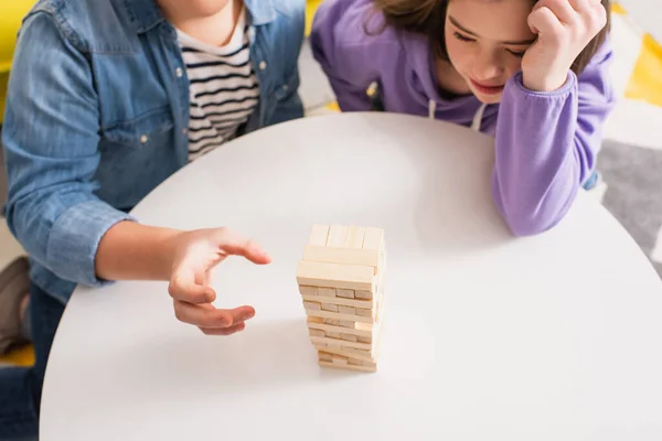 Visão superior do adolescente jogando jogo de blocos de madeira perto de amigo com síndrome de down em casa — Fotografia de Stock
