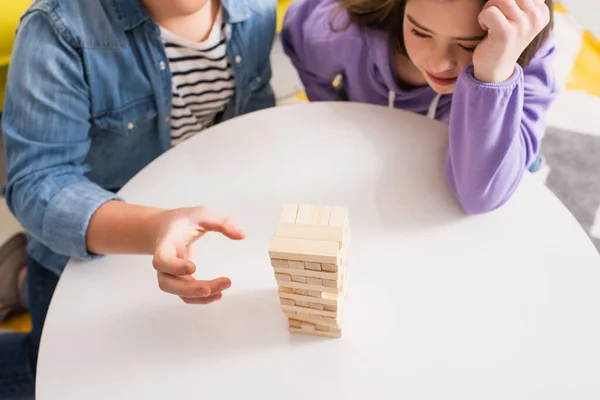 Vista superior de adolescente jugando bloques de madera juego cerca de amigo con síndrome de Down en casa - foto de stock