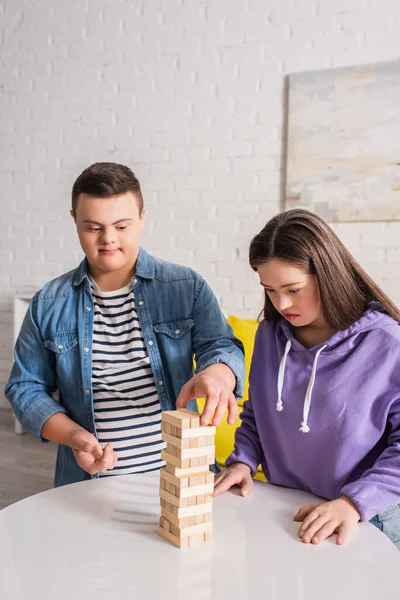 Друзья-подростки с синдромом пуха играют дома в деревянные блоки — стоковое фото