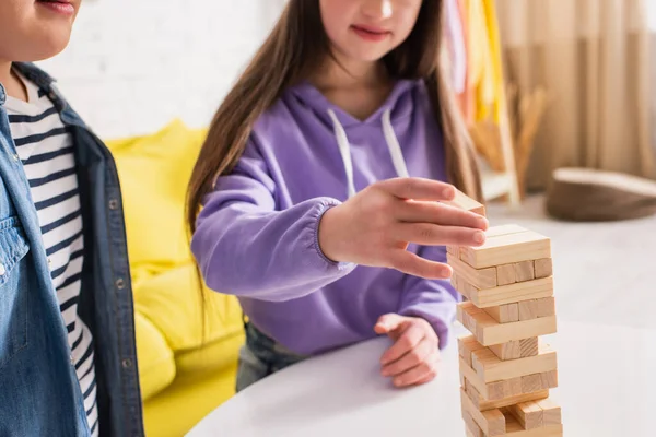 Vista recortada de adolescentes borrosos con síndrome de Down jugando bloques de madera juego en casa - foto de stock