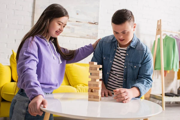 Позитивные друзья с синдромом Дауна играют в деревянные блоки игры на кофейном столике дома — стоковое фото