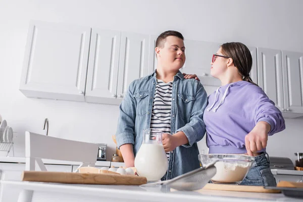 Visão de baixo ângulo de adolescente com síndrome de down cozinhar perto de namorado em casa — Fotografia de Stock