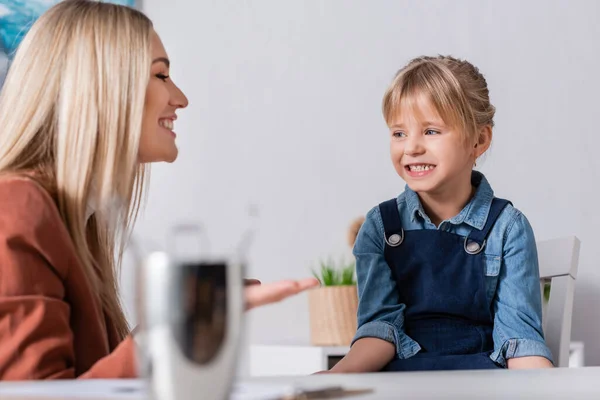 Chica sonriente mirando al terapeuta del habla durante la lección en la escuela — Stock Photo