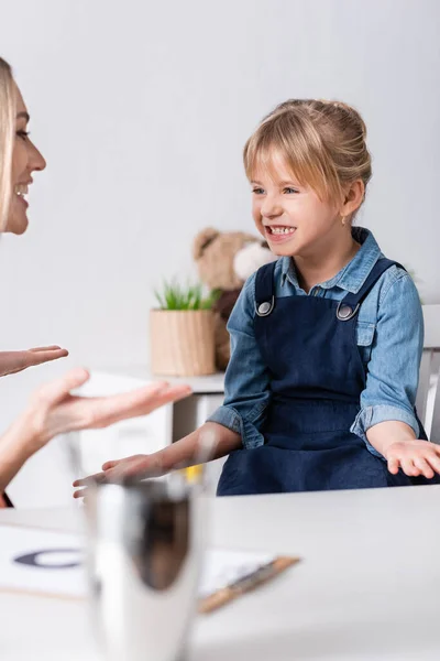 Gestos de niña mientras entrena articulación con logopedista en sala de consulta - foto de stock