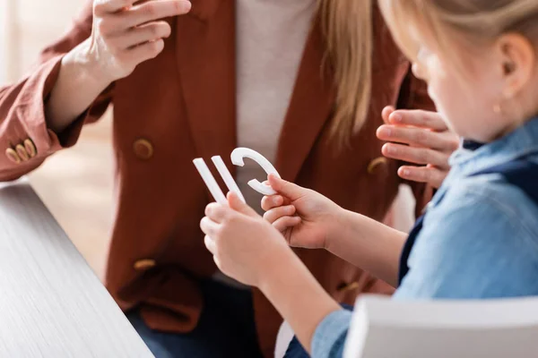 Blurred girl holding letters near speech therapist in consulting room — Stock Photo