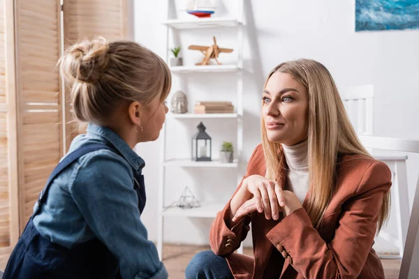 Speech therapist looking at pupil in classroom — стоковое фото