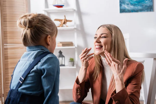 Orthophoniste parler près de fille floue dans la salle de classe — Photo de stock