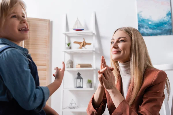 Lächelnder Logopäde blickt verschwommenes Mädchen im Klassenzimmer an — Stockfoto