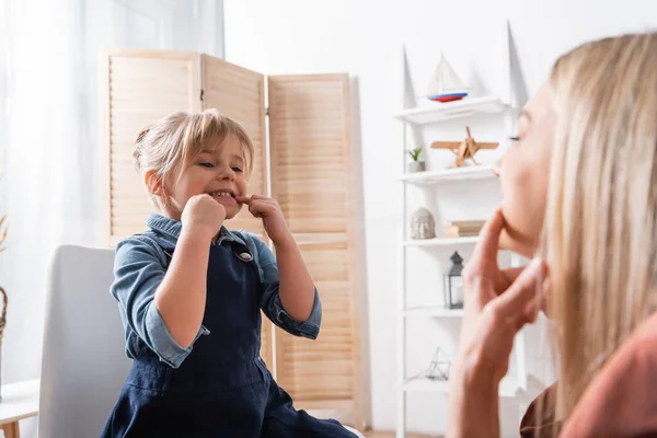 Smiling girl looking at speech therapist during lesson in classroom — Stock Photo