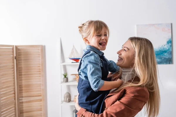 Positive speech therapist holding girl in classroom — Stock Photo