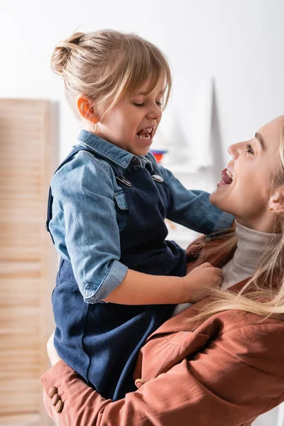 Speech therapist sticking out tongue and holding pupil in classroom — Stock Photo