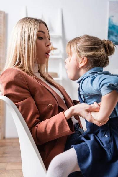 Terapeuta del habla y niño haciendo muecas en la sala de consulta - foto de stock