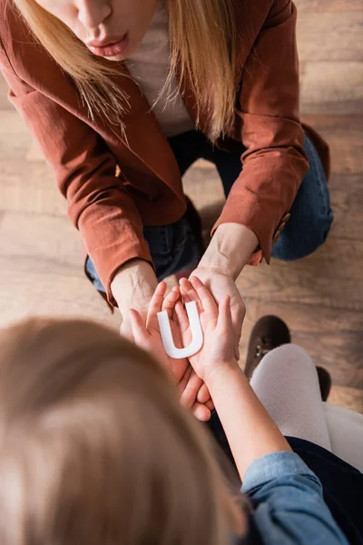 Vista aérea del niño sosteniendo carta cerca del terapeuta del habla en el aula — Stock Photo