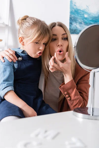 Speech therapist opening mouth near pupil and mirror in classroom — Stock Photo