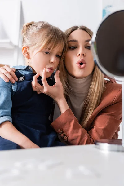 Logopeda abrir la boca cerca de chica y espejo borroso en el aula — Stock Photo