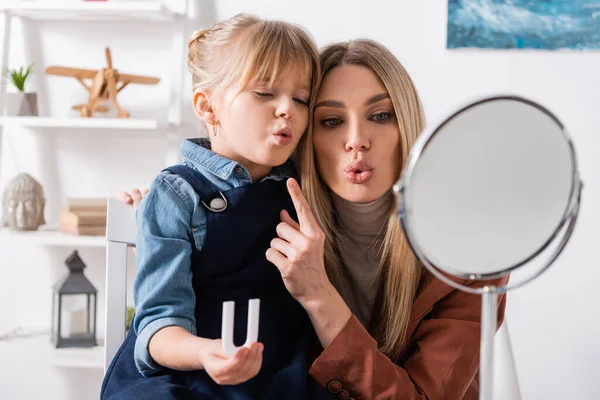 Pupil holding letter while talking near speech therapist and mirror in classroom — стоковое фото