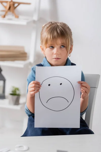 Skeptisches Kind hält lächelnd Zettel im Klassenzimmer — Stockfoto