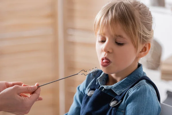 Speech therapist holding logopedic probe near schoolkid in classroom — Stock Photo