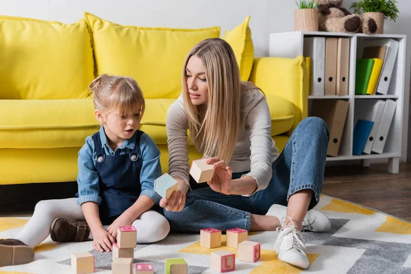 Terapeuta del habla sosteniendo bloques de madera cerca del niño en la sala de consulta - foto de stock