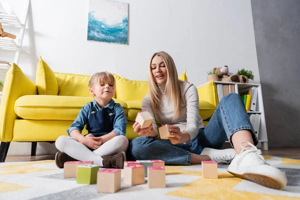 Speech therapist and girl sitting near wooden blocks during lesson in consulting room — Stock Photo