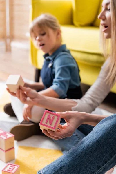 Blurred speech therapist holding wooden blocks during lesson with child in consulting room — Stock Photo