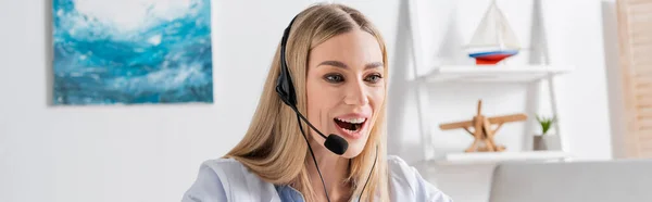Positive logopedist in headset having video call on laptop in consulting room, banner — Stock Photo