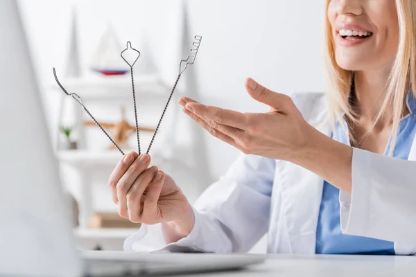 Cropped view of cheerful speech therapist pointing at  logopedic probes during video chat on laptop — Stock Photo