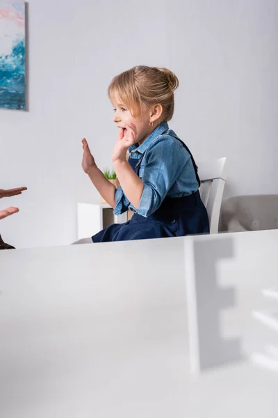Позитивна дитина говорить біля логопеда і розмитий лист в консалтинговій кімнаті — стокове фото