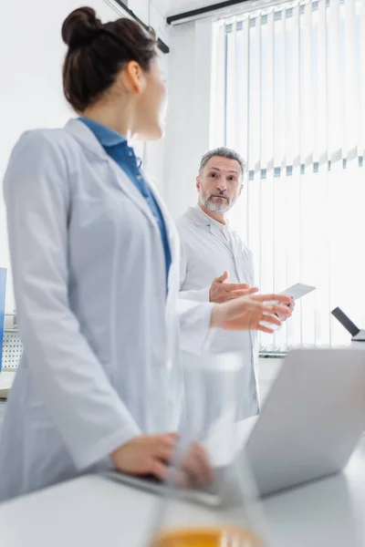 Bioengineers with gadgets gesturing and talking in laboratory — Stock Photo