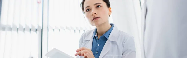 Jeune scientifique en manteau blanc tenant tablette numérique en laboratoire, bannière — Photo de stock