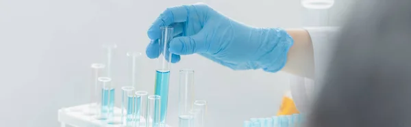 Partial view of scientist holding test tube with blue liquid, banner — Stock Photo