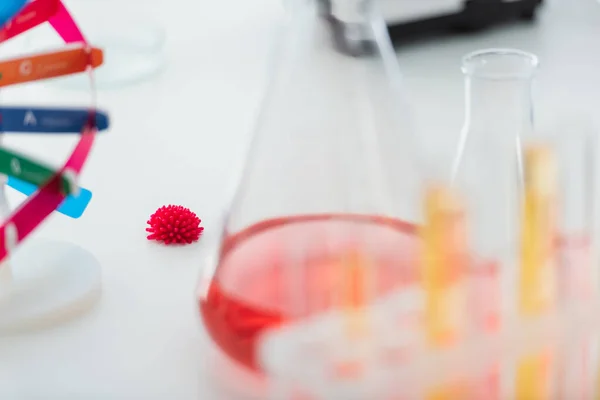 Selective focus of coronavirus bacteria model near blurred flasks in lab — Stock Photo