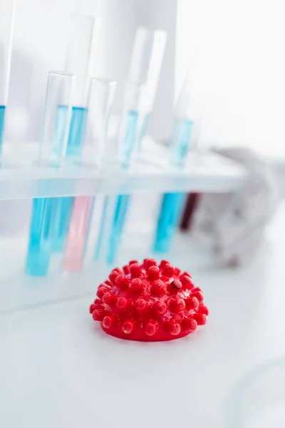 Close up view of coronavirus bacteria model near test tubes on blurred background — Stock Photo