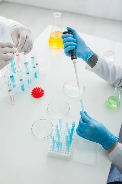 Cropped view of scientists working in lab near model of coronavirus bacteria — Stock Photo