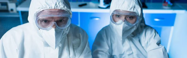 Bioingénieurs en combinaisons de matières dangereuses, lunettes et masques médicaux en laboratoire, bannière — Photo de stock