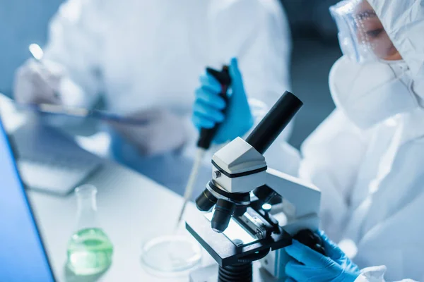 Selective focus of microscope near blurred bioengineer with micropipette in lab — Stock Photo