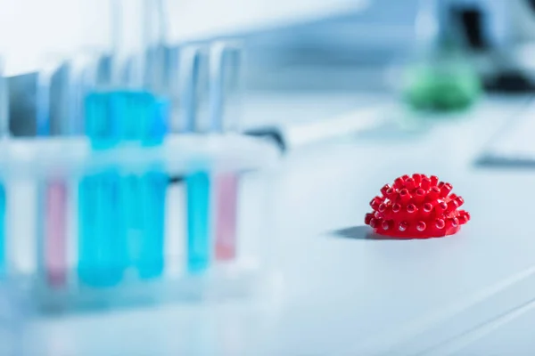 Selective focus of red coronavirus bacteria on blurred foreground in chemical lab — Stock Photo