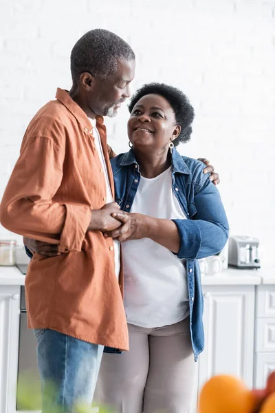 Feliz e sênior casal afro-americano de mãos dadas na cozinha — Fotografia de Stock