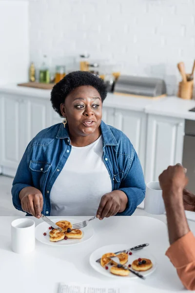 Mujer afroamericana mayor hablando con su marido durante el desayuno - foto de stock