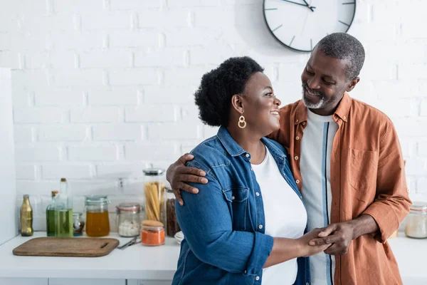 Feliz homem americano africano sênior olhando para a esposa na cozinha — Fotografia de Stock