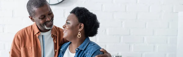 Feliz homem africano sênior americano olhando para a esposa na cozinha, banner — Fotografia de Stock